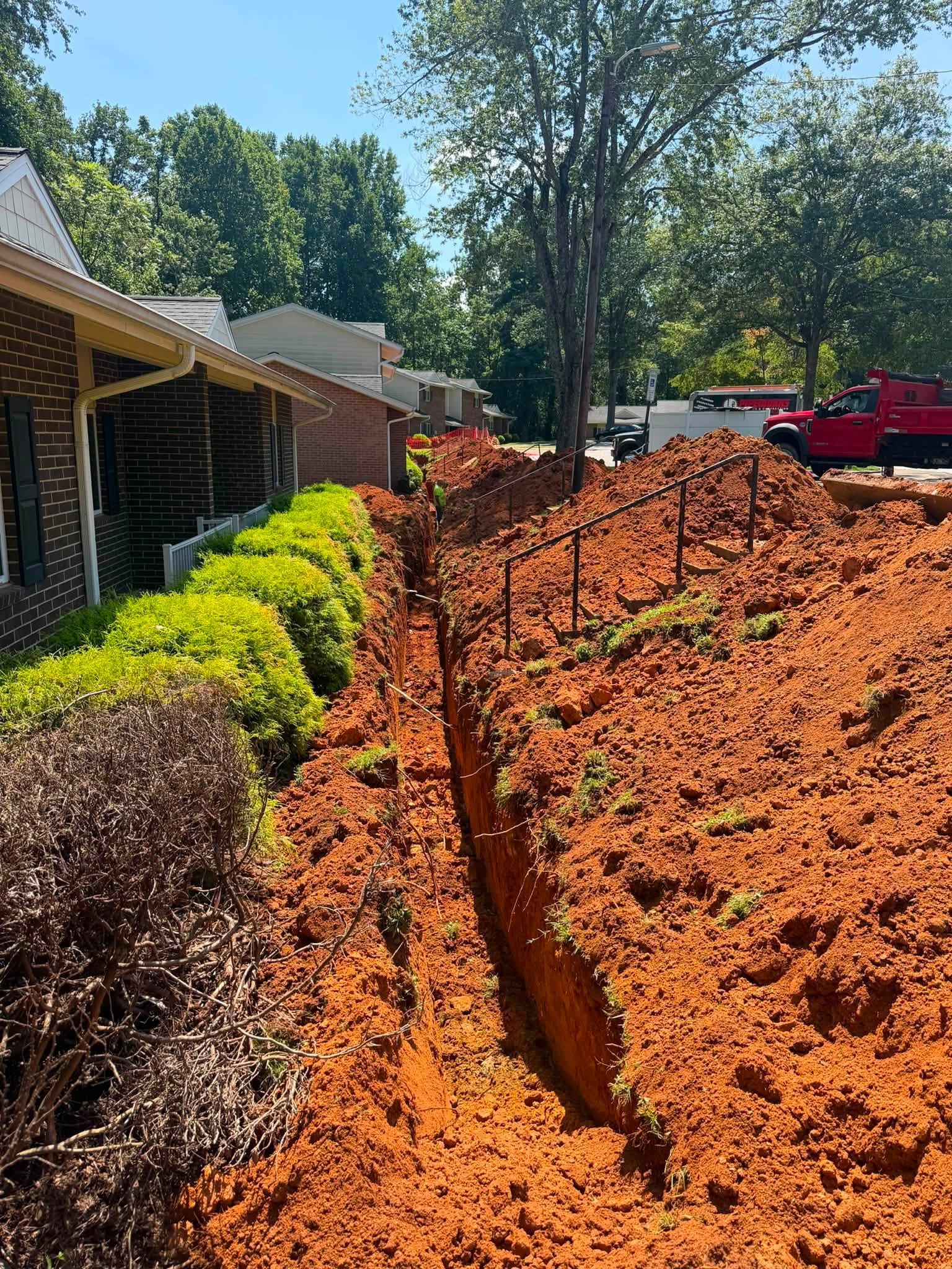 Full length of the open water line trench along the apartment building frontages with landscaping intact on the building side