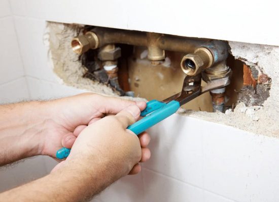 A Pipeworks Plumbing and Construction technician uses blue-handled pliers to repair exposed copper pipes inside a tiled wall, performing professional plumbing maintenance. A Pipeworks Plumbing and Construction technician uses blue-handled pliers to repair exposed copper pipes inside a tiled wall, performing professional plumbing maintenance.