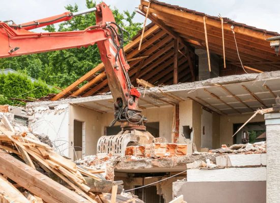 A yellow excavator from Pipeworks Plumbing and Construction demolishes the collapsed roof of a house, with debris and broken wooden beams scattered in the foreground due to severe plumbing damage, such as a failed main drain or basement pipe backup. A yellow excavator from Pipeworks Plumbing and Construction demolishes the collapsed roof of a house, with debris and broken wooden beams scattered in the foreground due to severe plumbing damage, such as a failed main drain or basement pipe backup.