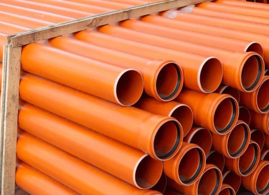 A stack of large orange plastic pipes from Pipeworks Plumbing and Construction, neatly secured in a wooden frame for safe transport or installation at commercial pipework and construction sites. A stack of large orange plastic pipes from Pipeworks Plumbing and Construction, neatly secured in a wooden frame for safe transport or installation at commercial pipework and construction sites.