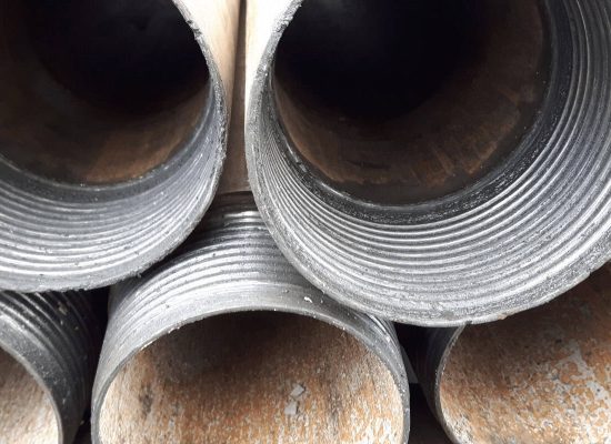 Close-up of stacked black metal pipes with visible screw threads and textured surfaces, commonly used in plumbing installations by Pipeworks Plumbing and Construction, highlighting circular pipe openings and industry wear. Close-up of stacked black metal pipes with visible screw threads and textured surfaces, commonly used in plumbing installations by Pipeworks Plumbing and Construction, highlighting circular pipe openings and industry wear.
